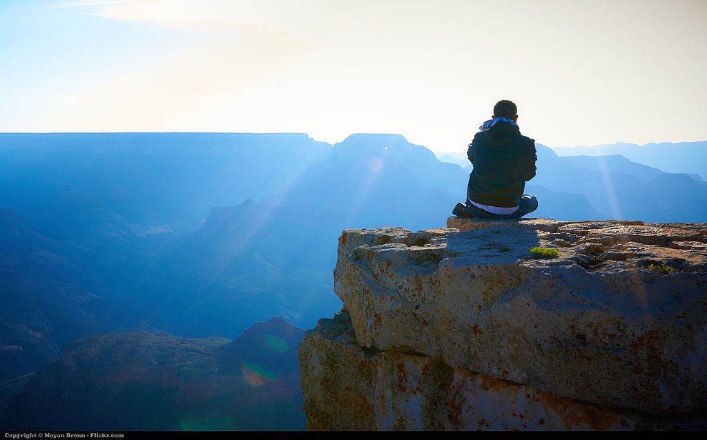 Can Silence Be Good for Your Health? 8 Young Man Meditatiing on cliff overlooking valley